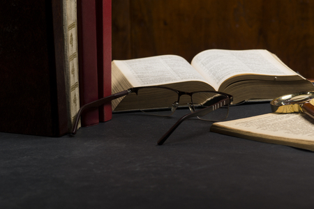Books with glasses on black table and wooden background. High resolution image depicting reading/bokks industry.の写真素材