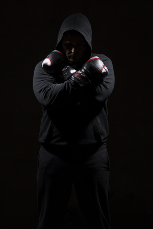Male adult with black hoodie on black background. High resolution image concept for boxing and fighting industry.の写真素材