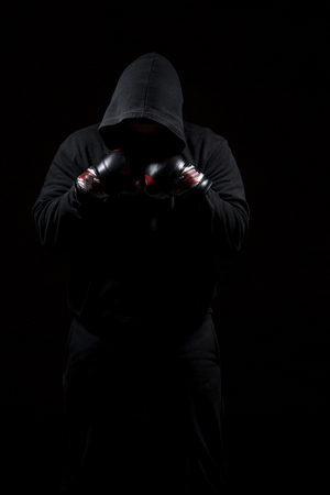 Male adult with black hoodie on black background. High resolution image concept for boxing and fighting industry.の写真素材