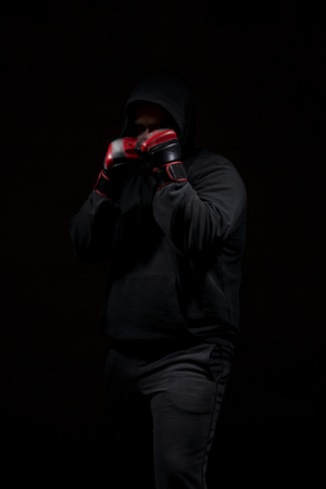 Male adult with black hoodie on black background. High resolution image concept for boxing and fighting industry.の写真素材