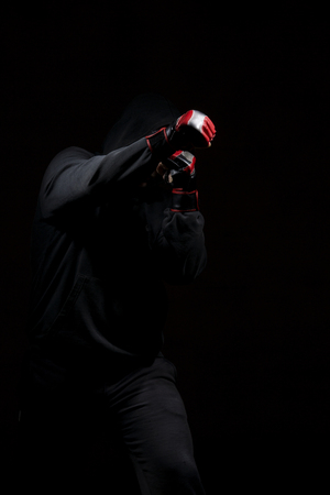 Male adult with black hoodie on black background. High resolution image concept for boxing and fighting industry.の写真素材