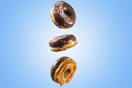 Chocolate glazed doghnut with sprinkled sweets on top on blue background. High resolution image for food industry.の写真素材
