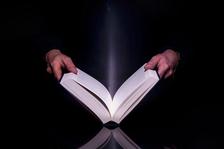 Person reading book with glowing light coming from inside of it. High resolutin image.