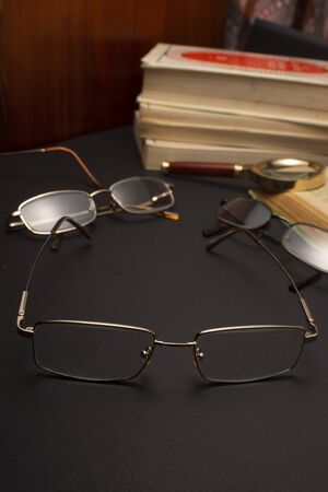 Books with glasses on black table and wooden background. High resolution image depicting reading/bokks industry.の写真素材
