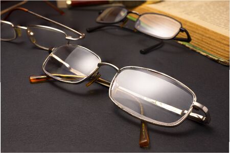 Books with glasses on black table and wooden background. High resolution image depicting reading/bokks industry.の写真素材