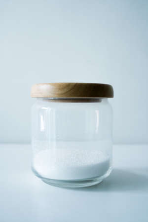 Glass jar with sugar on wooden white tableの写真素材