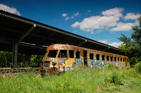 Rusty train in old railway station, Warsaw, Poland. Colorful graffiti, sunny day, blue sky and green...