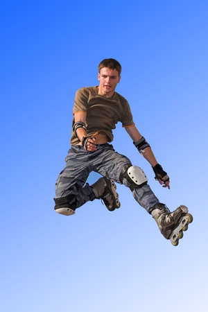 Active roller boy jumping from parapet on the blue skyの写真素材