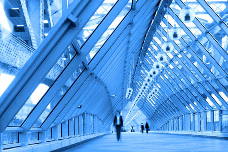 Blue glass corridor in bridge and people walking