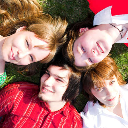 Four teenager lay on green grassの写真素材