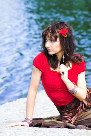 girl in red sit near waterの写真素材