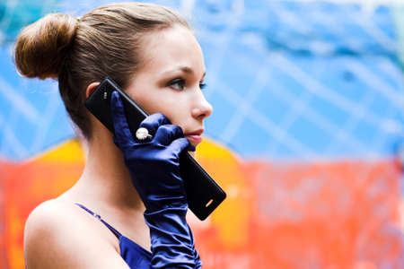 Teenager girl in blue talk by phone near colour wallの写真素材