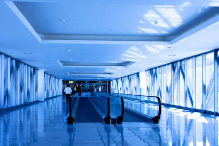 Person move in blue corridor with escalators in office centreの写真素材