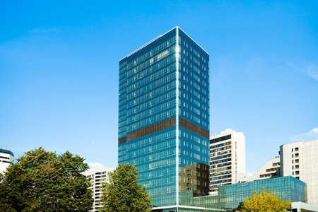 Blue glass business skyscraper tower between treesの写真素材