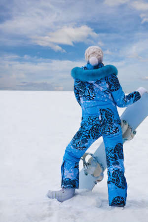 Snowboard girl in blue stay at the bottom of high hillの写真素材