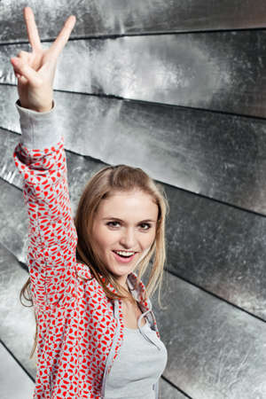 Portrait of young smiling girl showing gesture V-Victory!の写真素材