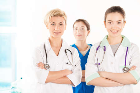 Two young doctors and nurse near the hospital windowの写真素材