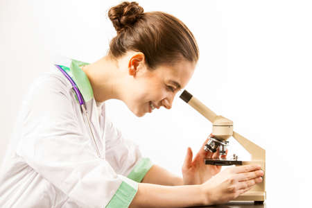 Young smiling doctor looking into a microscope