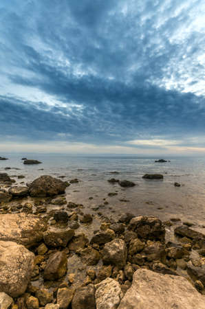 The rocky shore of the sea and the dramatic sky after sunsetの写真素材