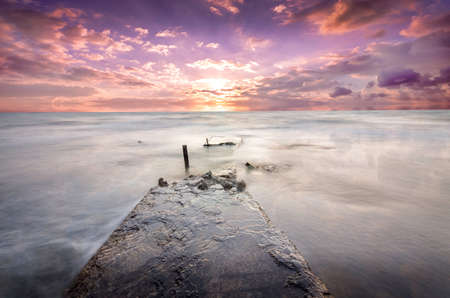 lonely destroyed pier extending deep into the ocean at sunsetの写真素材