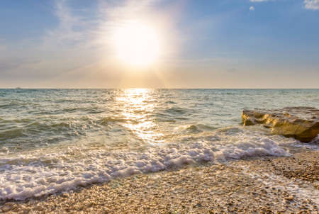 waves lapping on the pebble beach at sunsetの写真素材