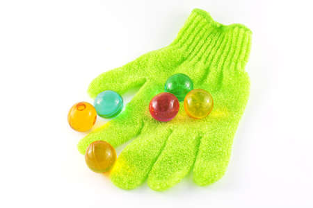 Bath glove with coloured bath pearls over white backgroundの写真素材