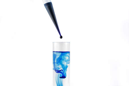 Test tube and dropper with blue drip over white backgroundの写真素材