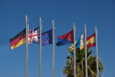 The Flags of Germany,United Kingdom,European Union,Lanzarote,Canary Islands and Spain under a blue skyの写真素材