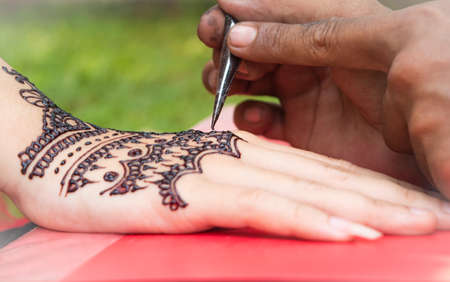 Woman right hand put on red book and painted with henna on wedding day