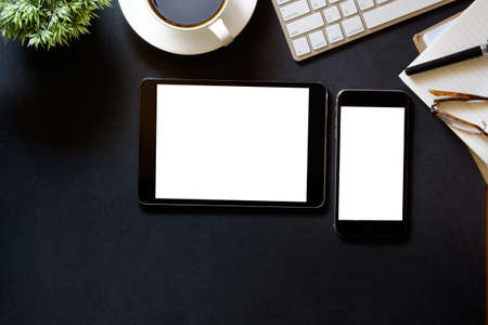 Modern dark surface office desk table with computer, Tablet , Smartphone with blank screen  and cup of coffee. Hero Header Concept.の写真素材
