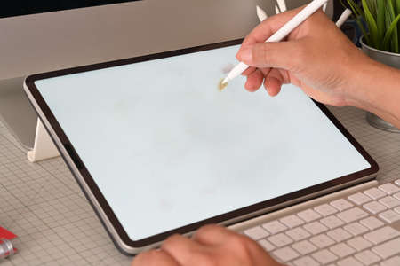 Graphic designer working with digital drawing tablet at studio workplace.