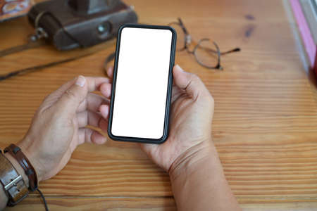 Top view man using a mobile smartphone over a wood workspace desk
