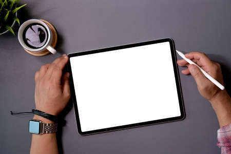 Man working on tablet computer with blank screen at office deskの写真素材