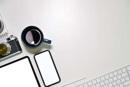 Office white desk with blank screen tablet, vintage camera, coffee mug and copy spaceの写真素材