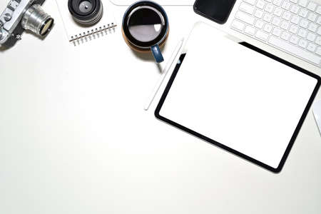 Office white desk with blank screen tablet, vintage camera, coffee mug and copy spaceの写真素材