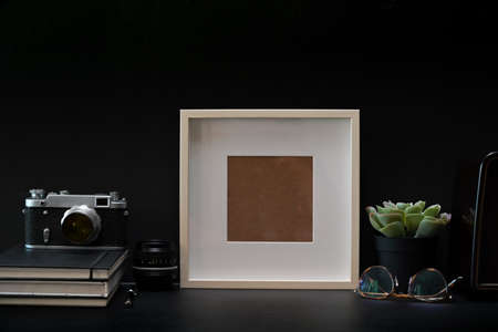 Mockup frame photo poster with books and vintage camera on dark table