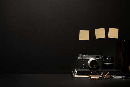 Dark leather desk with vintage camera, home office supplies and copy space
