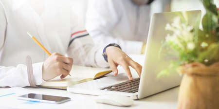 Closeup female freelancer writing on notebook while sitting in her working space