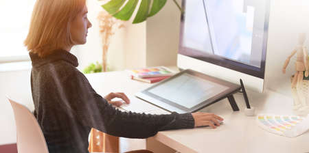 Beautiful young asian graphic designer working on computer using digital tablet in comfort working spaceの写真素材