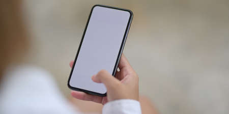 Close-up of woman's hands holding blank screen smartphone with blurred backgroundの写真素材