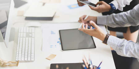 Development team brainstorming their upcoming project in modern office room while using tablet