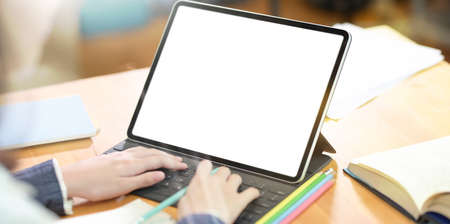 Close-up of young female typing on blank screen laptop in collage library with blurred background