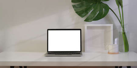 Freelancer's workplace with blank screen laptop and office supplies
