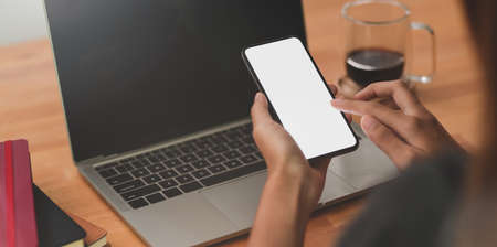 Young female freelancer's hands working while holding blank screen smartphoneの写真素材