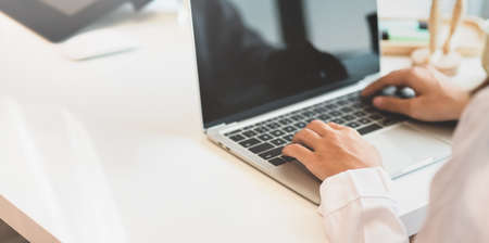 Young female freelancer working on laptop in minimal work place with blurred backgroundの写真素材