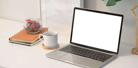 Blank screen laptop on white wooden desk in creative studio with decorationsの写真素材