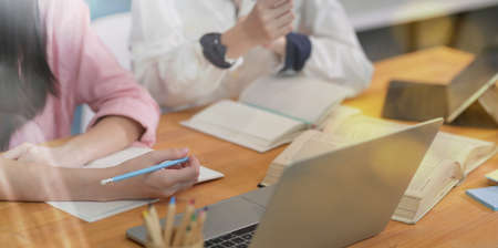Young students campus catching up and learning on wood desk