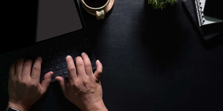 Top view of man's hands typing on laptop with black leather table in modern workspaceの写真素材