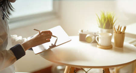 Close-up young female freelancer drawing her upcoming project on tablet in creative studioの写真素材