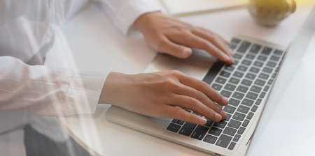 Close-up of female's hands typing and working in modern office room with blurred backgroundの写真素材